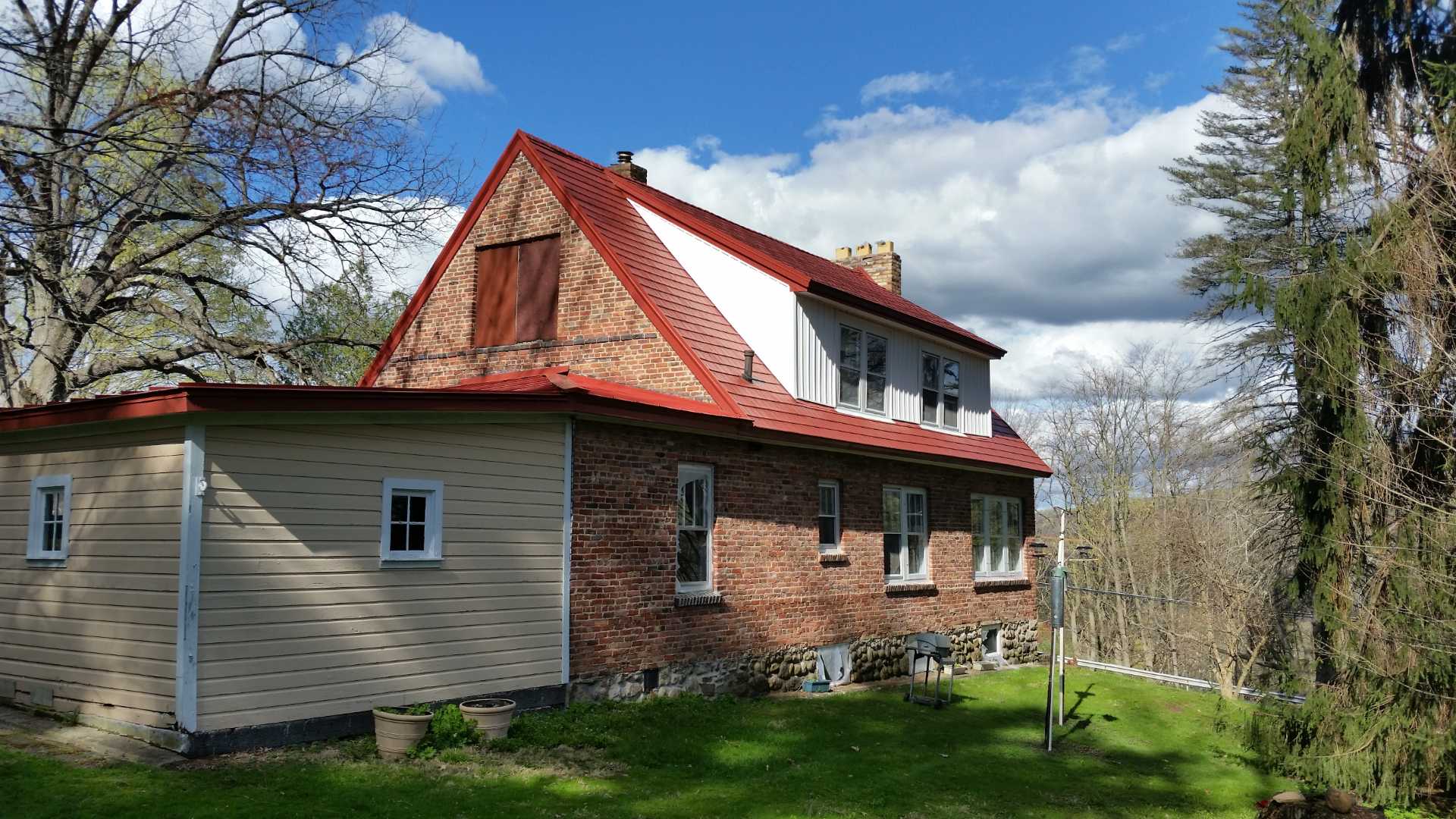 Rustic brick house with red metal roof.