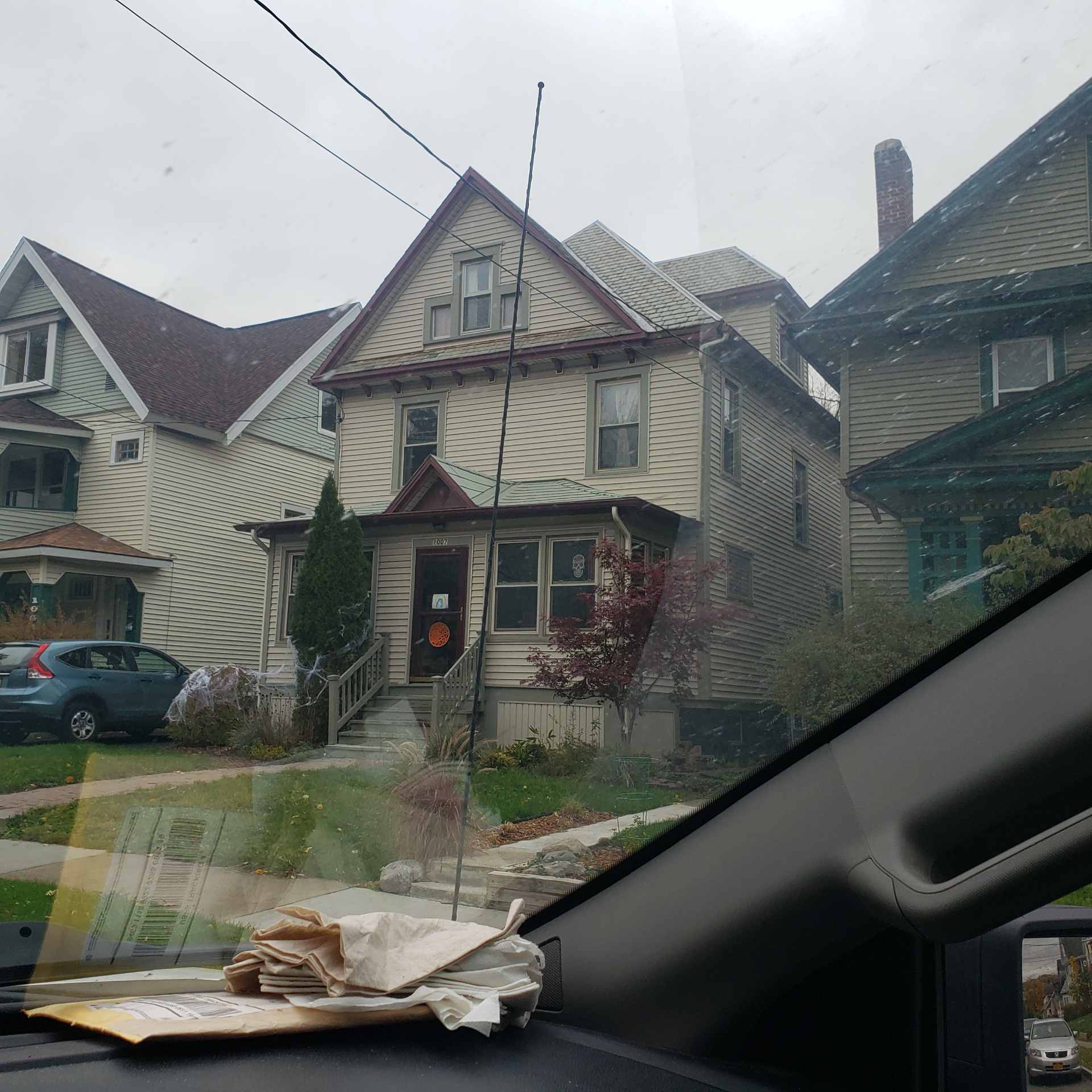 Old beige house viewed from car window.