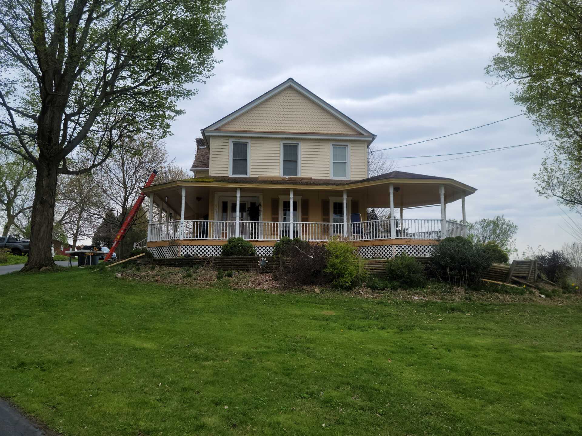 Farmhouse with wraparound porch and green lawn.