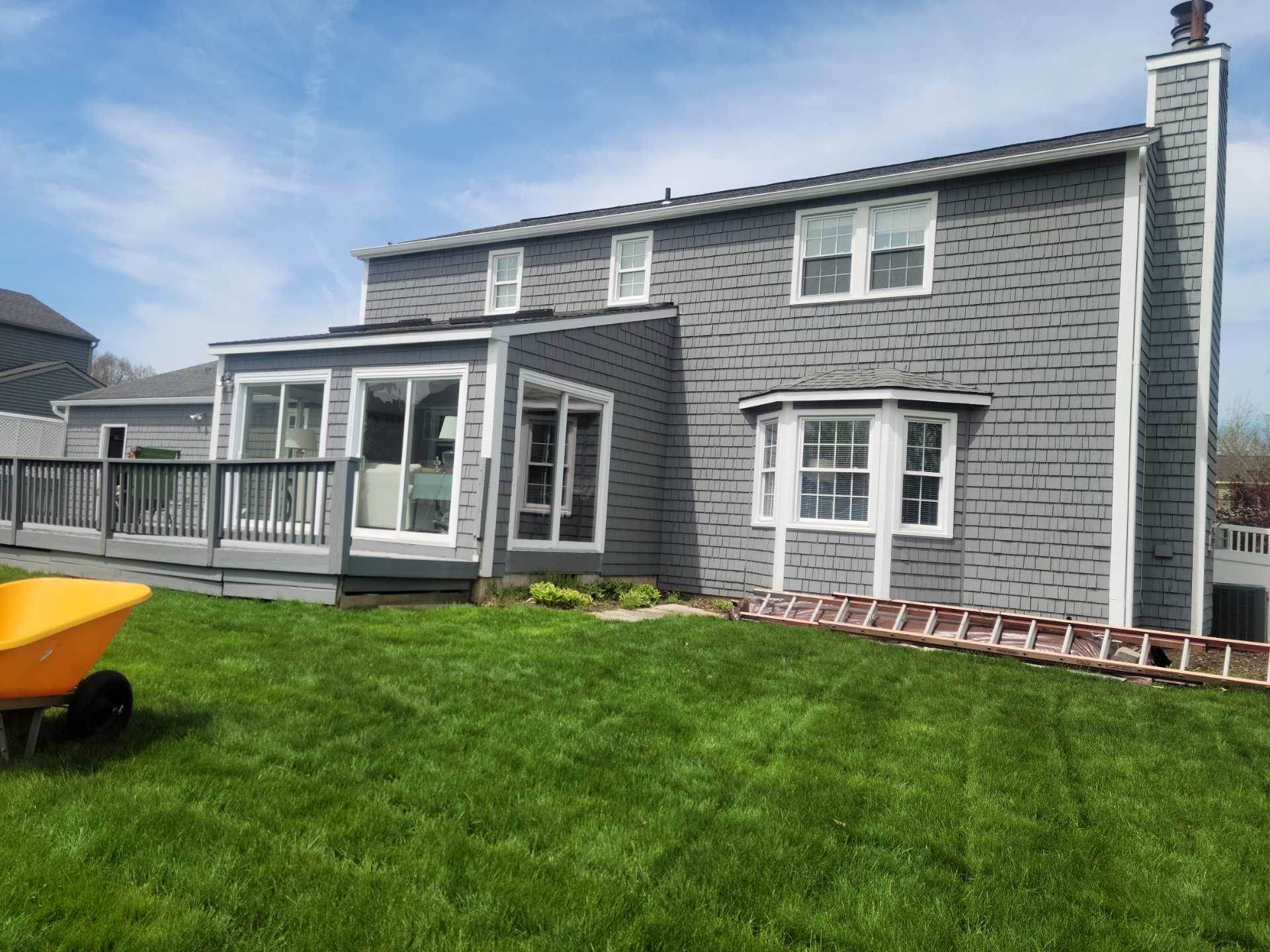 Modern gray house, green lawn, wooden ladder.