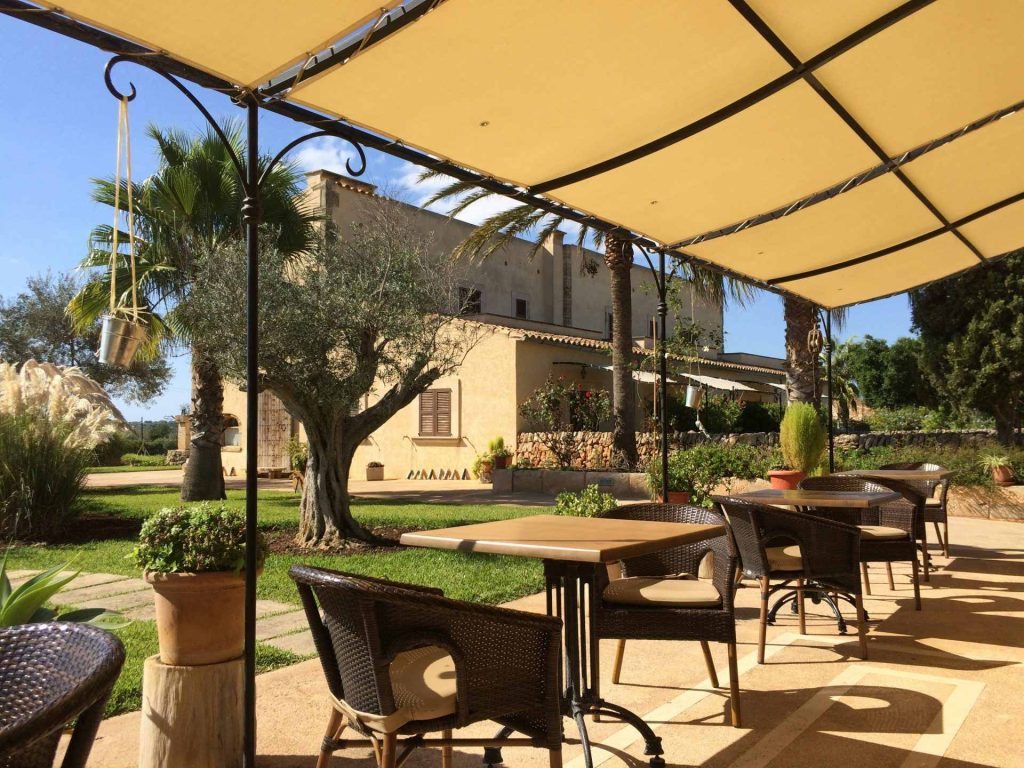 a patio with tables and chairs under an umbrella